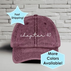 May include: A maroon baseball cap with the embroidered text "chapter 40" in white script. The cap has a curved brim and a fabric strap closure. The image also includes text that says "More Colors Available!"