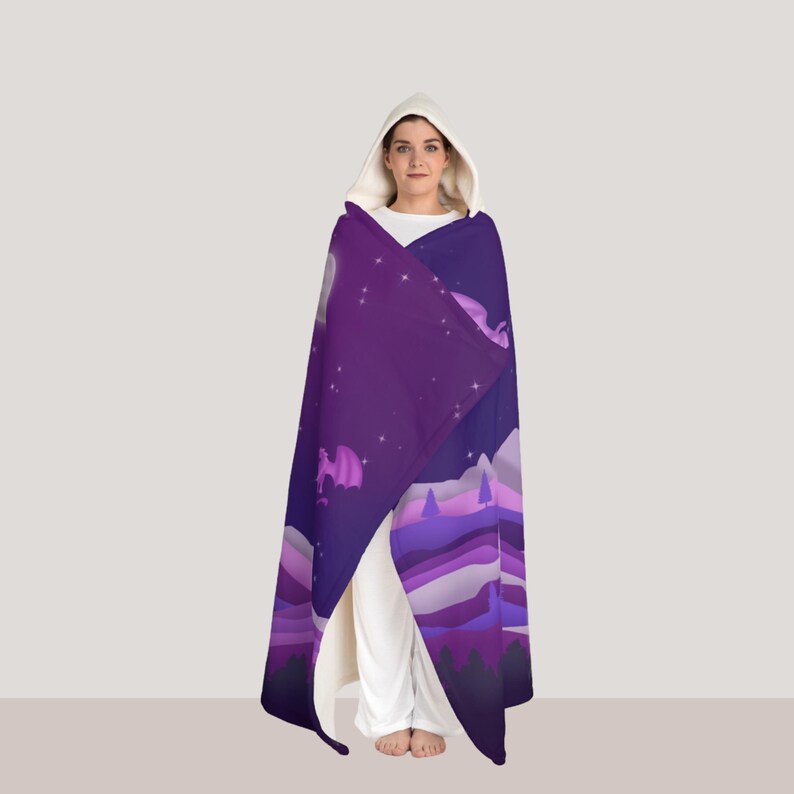 May include: A hooded cloak featuring a purple night sky design with dragons, mountains, and stars. The cloak is draped over a person wearing white clothing. The hood is white, and the cloak has a flowing, comfortable appearance.
