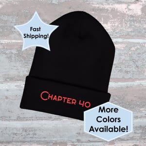 May include: A black beanie with the embroidered text "CHAPTER 40" in red. The hat is displayed against a weathered, light blue and white background. Additional text in the image reads "More Colors Available!" and "Fast Shipping!"