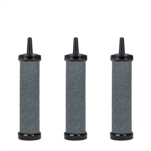 May include: Three cylindrical aquarium air stones. Each stone has a gray, porous body with a black top and base. The top of each stone has a black, tapered nozzle.