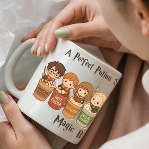 May include: White ceramic mug with a large handle, featuring cartoon characters and the text "A Perfect Potion" and "Magic Brew". The mug has illustrations of characters in coffee cups labeled "Mocha Latte", "Hot Cocoa", "Cappuccino", and "Milk Shake".