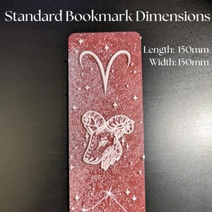 May include: A red bookmark with white Aries zodiac symbols and star accents. The bookmark is 150mm long and 150mm wide. The text "Standard Bookmark Dimensions" is at the top.