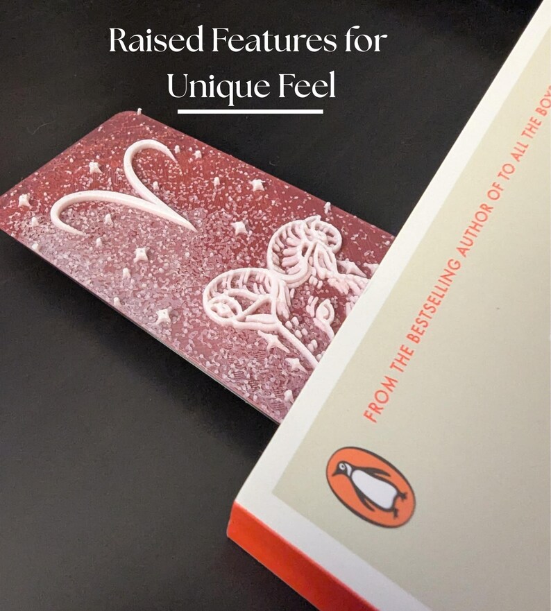 May include: A red bookmark with white raised features, including a heart and floral design, is placed in a book. The book has a Penguin logo and the text "FROM THE BESTSELLING AUTHOR OF TO ALL THE BOYS". The bookmark has the text "Raised Features for Unique Feel".