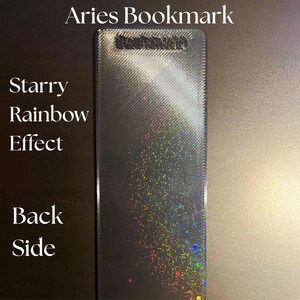 May include: A rectangular bookmark with a starry rainbow effect. The text "Aries Bookmark" is at the top, and "Starry Rainbow Effect" and "Back Side" are on the left side. The bookmark has a textured surface.