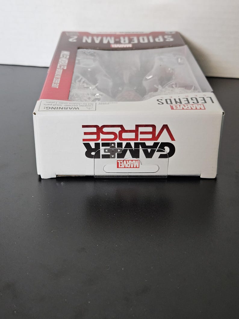 May include: A boxed Marvel Legends Gamerverse Spider-Man 2 action figure. The box is white with red accents and features the Marvel logo, the words "Gamerverse" and "Spider-Man 2". The figure is visible through a clear plastic window.
