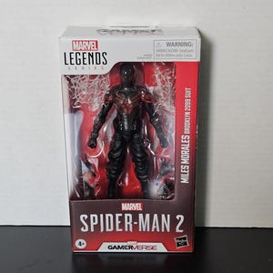 May include: A boxed Marvel Legends action figure of Miles Morales in his Brooklyn 2099 suit. The figure is black with red detailing and is from the Spider-Man 2 Gamerverse series. The packaging includes a warning for small parts and is for ages 4+.
