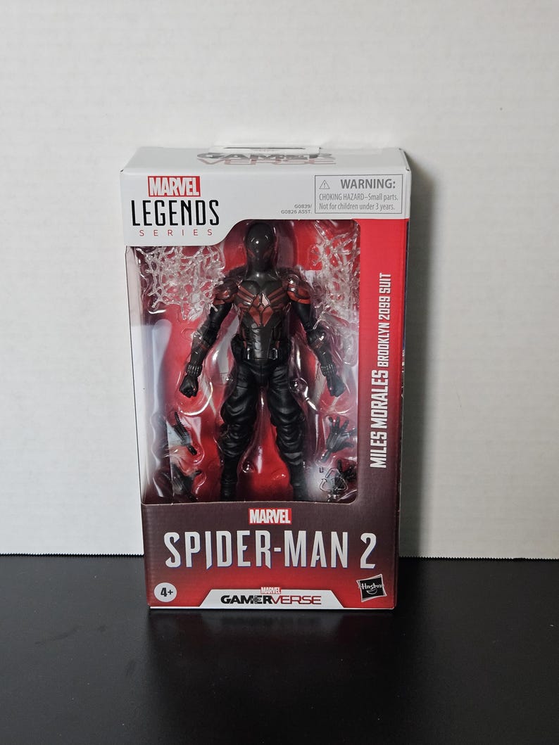 May include: A boxed Marvel Legends action figure of Miles Morales in his Brooklyn 2099 suit. The figure is black with red detailing and is from the Spider-Man 2 Gamerverse series. The packaging includes a warning for small parts and is for ages 4+.