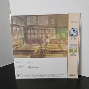 May include: A vinyl record featuring artwork of a classroom scene with two children. The album cover includes Japanese text and a smaller image of a seaside scene. The record is in a clear plastic sleeve.