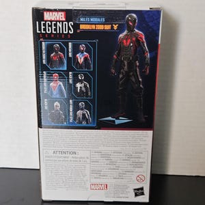 May include: A Marvel Legends Series action figure box featuring Miles Morales in the Brooklyn 2099 suit. The box has images of other suits, including the Boricua Suit and Black Suit. The box is black, red, and white.
