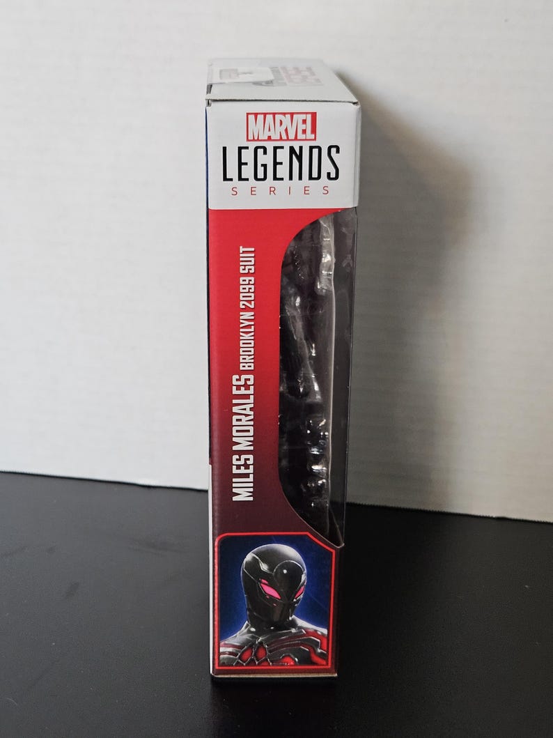 May include: A Marvel Legends Series action figure box featuring Miles Morales in his Brooklyn 2099 suit. The box has a red and white colour scheme with the Marvel Legends logo at the top. The figure is visible through a clear plastic window.