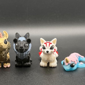 May include: Six small, stylised animal figurines are displayed. The collection includes a unicorn, a squirrel-like creature, a bear-like figure, a fox, a sleeping unicorn, and a dragon-like creature. Each figure is detailed with various colours.