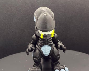 May include: A black and white figurine of a creature with a textured head, blue eyes, and yellow accents. The figurine has a detailed design and is posed on a black surface. The creature has a unique, stylized appearance.