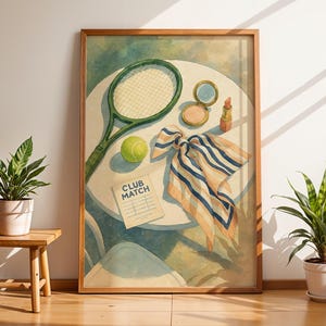 May include: A framed watercolor print featuring a tennis racket, ball, and a "Club Match" paper on a table. A scarf with blue and white stripes, makeup, and lipstick are also on the table. The print has a wooden frame.
