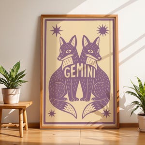 Puede incluir: Un p&oacute;ster enmarcado con dos zorros morados estilizados, con la palabra "GEMINI" en el centro. El fondo es de color amarillo claro, y el p&oacute;ster est&aacute; en un marco de madera. El dise&ntilde;o tambi&eacute;n incluye estrellas. Ideal para la decoraci&oacute;n del hogar.