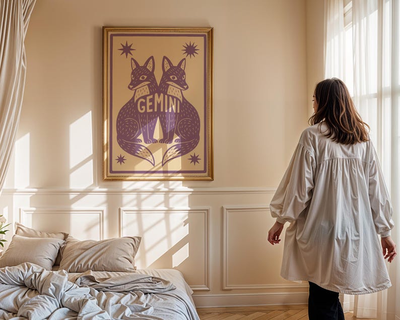 Puede incluir: Una impresi&oacute;n art&iacute;stica enmarcada con dos zorros morados enfrentados, con la palabra "Gemini" en el centro. La obra de arte est&aacute; sobre un fondo beige con acentos de estrellas y un marco dorado. La impresi&oacute;n se exhibe en un dormitorio.