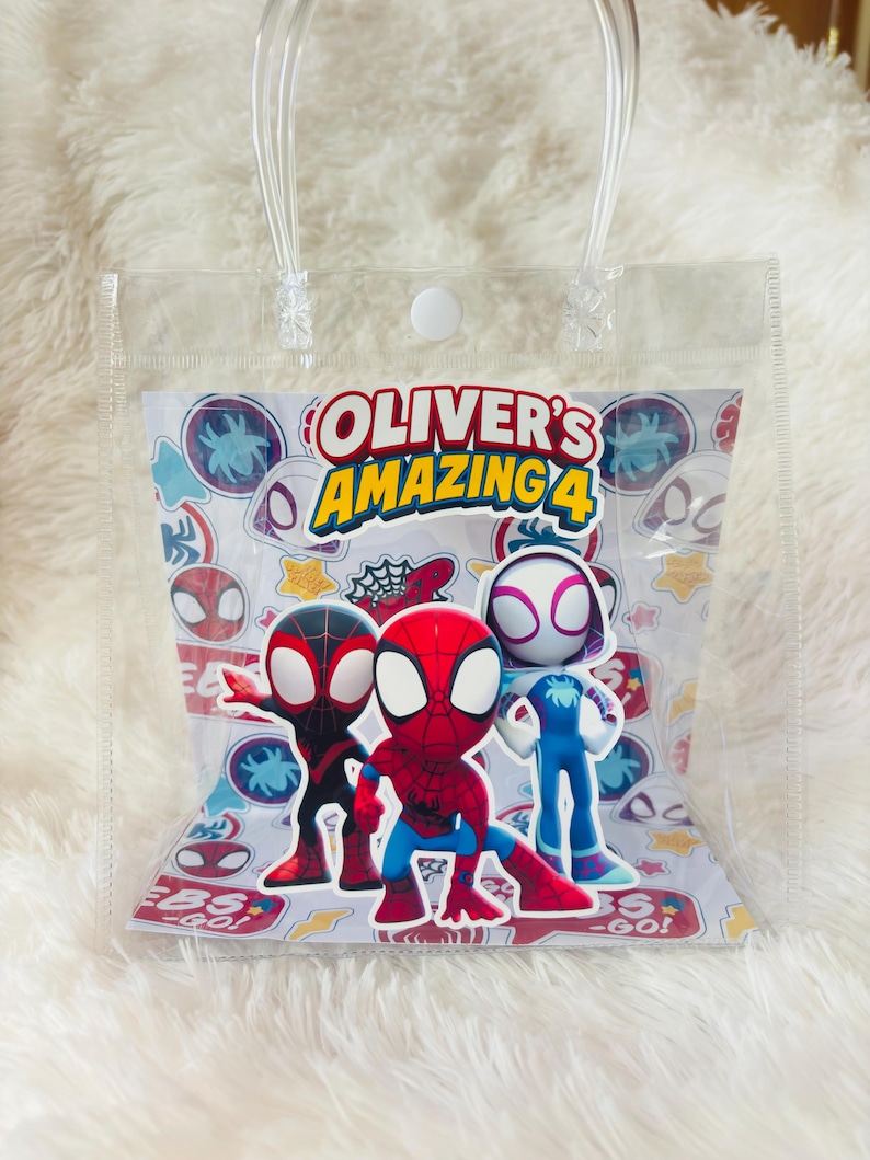 May include: Clear plastic gift bag with a handle, featuring the text "OLIVER'S AMAZING 4" and illustrations of Spider-Man characters. The bag has a white background with various Spider-Man-themed icons and the words "EBS - GO!"
