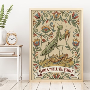 May include: A framed art print featuring a green praying mantis holding a smaller insect, with the text "GIRLS WILL BE GIRLS" on a banner. The artwork has a floral border with red, blue, and orange accents.