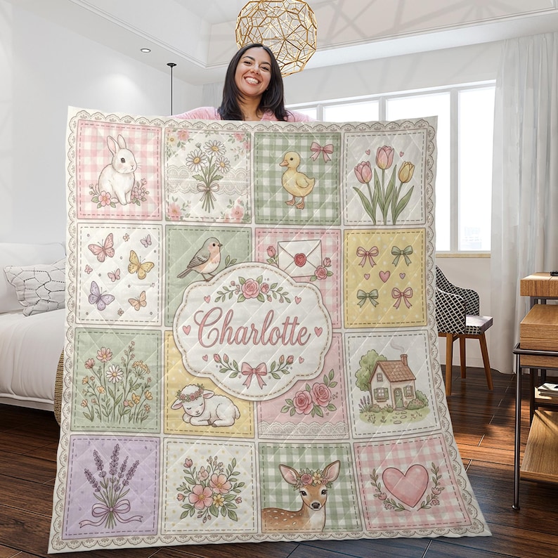 May include: A quilted blanket featuring a grid of pastel-coloured squares with illustrations of a rabbit, flowers, a duckling, tulips, butterflies, a bird, an envelope, bows, a lamb, a house, lavender, and a deer, with the name Charlotte in the centre.