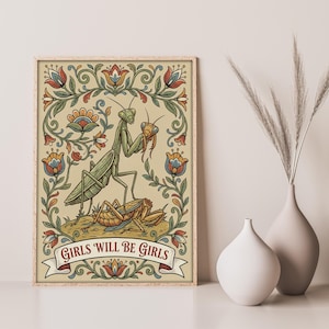May include: A framed art print featuring a green praying mantis with a smaller insect, surrounded by floral designs in red, blue, and yellow. The banner at the bottom reads "GIRLS WILL BE GIRLS".