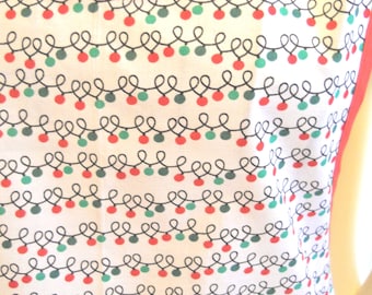 May include: A sleeveless top with a white base featuring a repeating pattern of black looped lines and small red and green circular accents. The garment has a round neckline and armholes trimmed with a solid coral-colored fabric binding.
