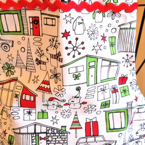 May include: A white fabric stocking featuring a repeating black line art pattern of mid-century modern houses, cars, reindeer, snowmen, and gift boxes with red and green accents. A horizontal red rickrack trim is sewn across the upper section.