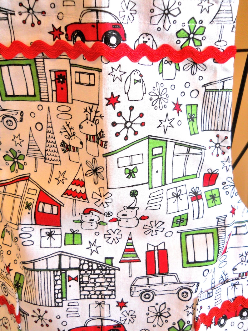 May include: A white fabric stocking featuring a repeating black line art pattern of mid-century modern houses, cars, reindeer, snowmen, and gift boxes with red and green accents. A horizontal red rickrack trim is sewn across the upper section.