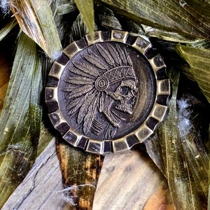 Deep engraved brass coin with an Indian skull pictured.
