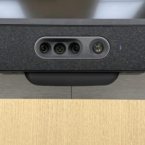 Puede incluir: Un dispositivo de videoconferencia Cisco negro montado debajo de un televisor. El dispositivo tiene tres lentes y una pequeña luz. La palabra "AFTER" se muestra en letras verdes encima del dispositivo.