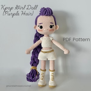 Puede incluir: Muñeca Kpop Girl de ganchillo con cabello morado, que lleva una camiseta, pantalones cortos y botas blancas con detalles dorados. La muñeca tiene un peinado largo y trenzado y está etiquetada como "PDF Pattern". El texto "Kpop Girl Doll (Purple Hair)" está en la parte superior.