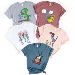 May include: A collection of five graphic t-shirts in various colors, each featuring cartoon bug characters. Designs include a bug with a leaf, a bug lifting toilet paper, and a ladybug relaxing. The shirts are displayed on a white surface.