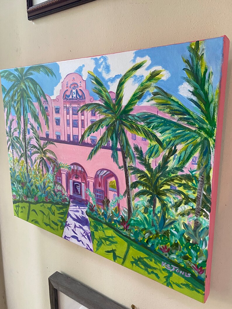 May include: A painting depicting a pink building with palm trees and a pathway in front. The building has white trim and a sign that reads "The Breakers". The painting is signed "K. Jones".