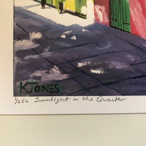 May include: A watercolor painting of a street scene in the French Quarter of New Orleans. The painting is signed "K. Jones" and numbered "1/250" in the lower right corner. The title of the painting is "Sunlight in the Quarter".