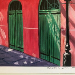 May include: A painting of a red brick building with three green doors. The doors are arched and have a simple design. The building is in a shaded area, and the light is coming from the right side of the image. The painting is signed "Krista C. Jones 2019".