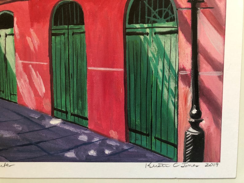 May include: A painting of a red brick building with three green doors. The doors are arched and have a simple design. The building is in a shaded area, and the light is coming from the right side of the image. The painting is signed "Krista C. Jones 2019".
