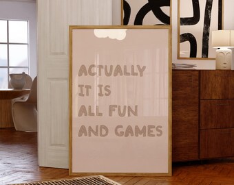 May include: A framed poster with the text "ACTUALLY IT IS ALL FUN AND GAMES" in a light brown font. The poster is displayed in a room with other framed art and wooden furniture. The overall color scheme is neutral with a focus on light browns and whites.