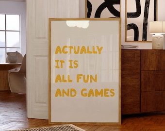 May include: A framed art print with the text "ACTUALLY IT IS ALL FUN AND GAMES" in yellow letters. The print is displayed in a room with wooden floors and other framed art pieces.