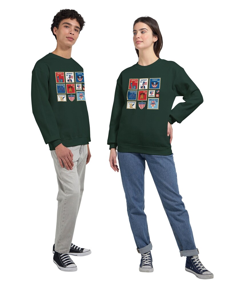 May include: Two people wearing matching dark green sweatshirts. The sweatshirts display a grid of colourful postage stamp designs with patriotic themes. The stamps include images of eagles, flags, and other symbols. One person wears light grey trousers, the other blue jeans.