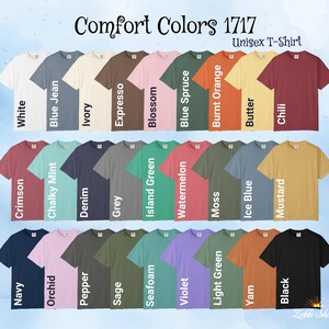 Op de afbeelding: Een display van Comfort Colors 1717 unisex t-shirts in verschillende kleuren, waaronder wit, blue jean, ivoor en zwart. De afbeelding toont een reeks tinten, van pasteltinten tot gedurfde tinten, waarbij elk shirt is gelabeld met zijn kleurnaam.