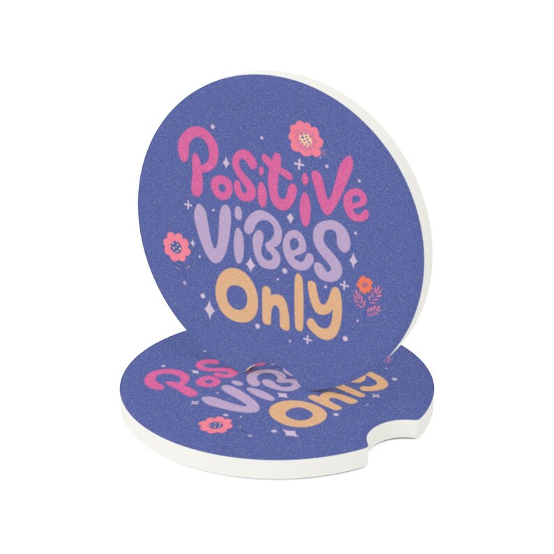 以下が含まれることがあります： 青い背景に「Positive Vibes Only」の文字がピンク、紫、黄色で書かれた、丸い車のコースター2枚。コースターは白い縁取りがあり、取り出しやすいように切り込みが入っています。