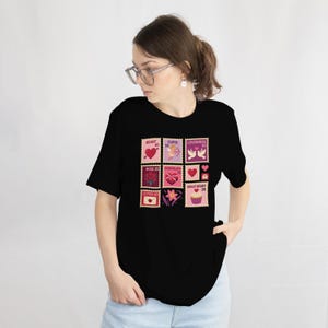 Op de afbeelding: Zwart T-shirt met een kleurrijk stempelontwerp met Valentijnsdagthema's. De postzegels tonen harten, Cupido, tortelduifjes, rozen, chocolade en een cupcake. Het shirt is gemaakt van een zacht materiaal.