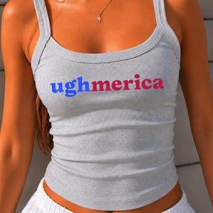 Pu&ograve; includere: Una canotta a coste grigio melange con la scritta ughmerica stampata sul petto. La parola ugh &egrave; blu, mentre merica &egrave; rossa. Il capo presenta uno scollo rotondo e spalline larghe. Il testo ATHLETIC HEATHER &egrave; visibile nell'immagine.