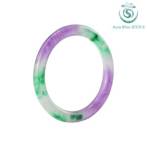 Könnte beinhalten: Ein runder Jade-Armreif in Lila, Grün und Weiß. Der durchscheinende Stein ist poliert und glatt, mit einem Farbverlauf. Der Armreif ist ein Schmuckstück.