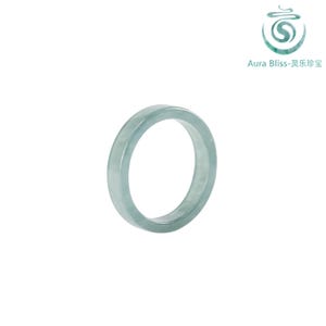 May include: A light green jade ring. The ring is a solid band with a smooth, polished surface. The Aura Bliss logo is in the upper right corner.