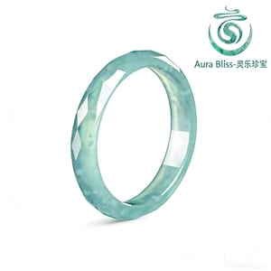 May include: A light blue jade bangle bracelet with a faceted design. The bracelet has a translucent quality, allowing light to pass through. The Aura Bliss logo is visible in the upper right corner.