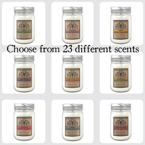May include: Nine glass jars with silver lids containing candles. Each jar has a label with a different scent name, including Pine, Pink Sugar, Amber, Nag Champa, Orange Vanilla Clove, Lemongrass, Rose Petal, Ocean, and White Tea Ginger. The text "Choose from 23 different scents" is displayed below the jars.