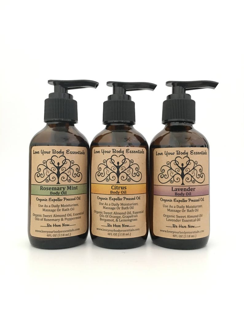 May include: Three brown glass bottles of body oil with black pump dispensers. Each bottle has a label with text, including "Rosemary Mint", "Citrus", and "Lavender". The labels also state the oil is organic and expeller pressed.