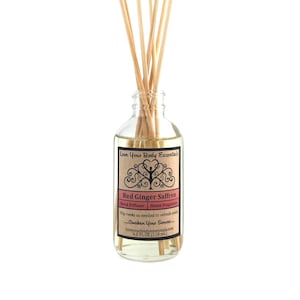 May include: A clear glass bottle with a brown label that reads "Love Your Body Essentials" and "Red Ginger Saffron Reed Diffuser Home Fragrance". The label also includes the text "Flip reeds as needed to refresh scent -Awaken Your Senses- loveyourbodyessentials.com 4.0 FL OZ (118 ml.)". The bottle is filled with a clear liquid and has wooden sticks inserted into it.