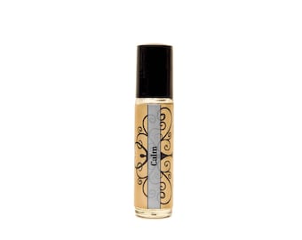 May include: A clear glass roller bottle with a black cap and a label that says "Calm" in a decorative font. The label is surrounded by a brown floral design.