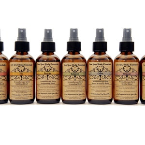 May include: Eight amber glass bottles with spray tops, each labeled with a different aromatherapy blend. The labels feature a stylized tree design and the words "Love Your Body Essentials". The blends are Clarity, Joy, Energy, Balance, Calm, Dream, and Passion.