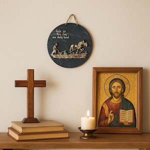 May include: A wooden cross, two books, a framed religious icon, a candle in a brass holder, and a round plaque with a relief of a farmer plowing with horses. The plaque has the text "Give us this day our daily bread."